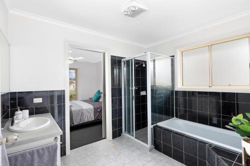 a bathroom with a sink and a bath tub and a bed at Maggie's Place in Mount Gambier