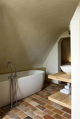 a bathroom with a white tub and a sink at Landhuis Eikenburg in Ypres