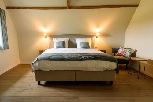 a bedroom with a large bed and a chair at Landhuis Eikenburg in Ypres