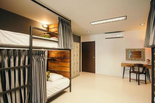 een slaapkamer met een stapelbed en een bureau bij KoHabitat Samui in Bophut 