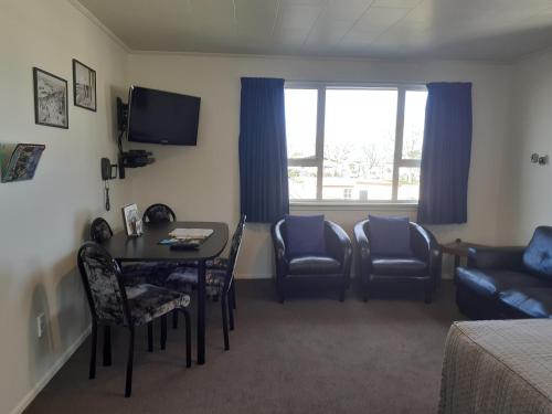 a room with a table and chairs and a couch at AAA Thames Court Motel in Oamaru