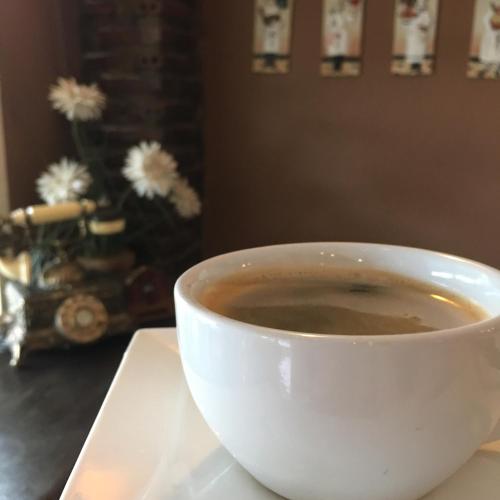 a white cup of coffee sitting on a table at The Green land (Khok Kruat) in Nakhon Ratchasima