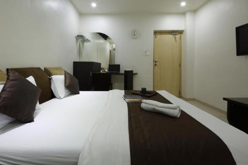 a bedroom with a large white bed with a television at Hotel Volga in Ahmedabad