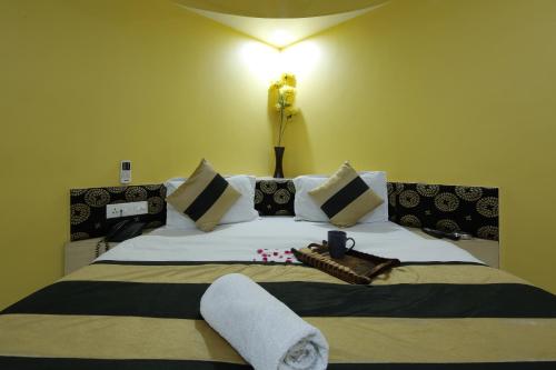 a bedroom with a large bed with white sheets and pillows at Hotel Volga in Ahmedabad