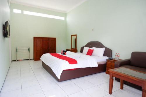 a bedroom with a large bed and a couch at RedDoorz Plus near Stadion Wijaya Kusuma in Cilacap