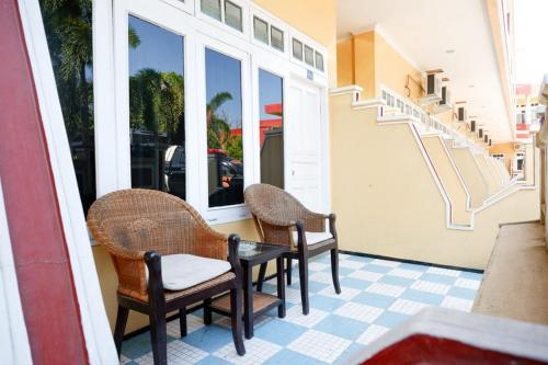 a porch with two chairs and a table and windows at RedDoorz Plus near Stadion Wijaya Kusuma in Cilacap