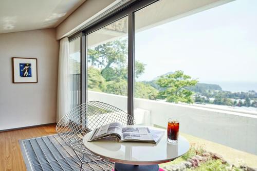 a table with a book and a drink on a balcony at Jeju Bom stay & Art Gallery in Seogwipo