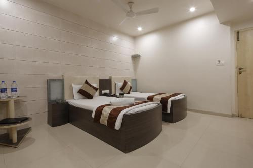 a bedroom with two beds and a tv in it at Hotel Volga in Ahmedabad