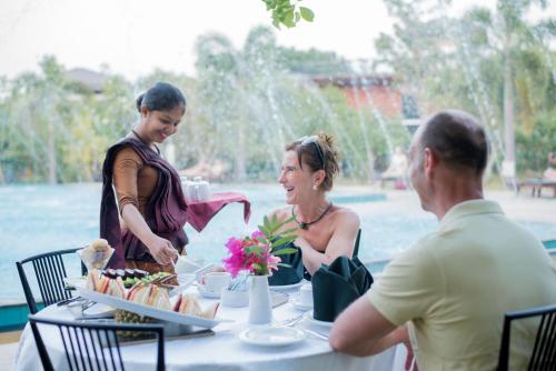 a group of people sitting around a table with food at Sungreen Resort Habarana in Habarana