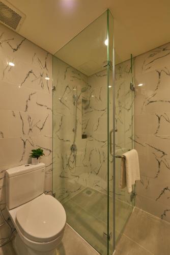 a bathroom with a toilet and a glass shower at Zazz Urban Ho Chi Minh in Ho Chi Minh City