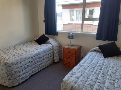 a bedroom with two beds and a window with blue curtains at AAA Thames Court Motel in Oamaru