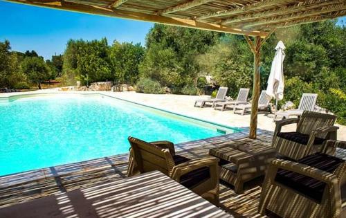 a swimming pool with chairs and a table next to it at Agriturismo Grotta Di Figazzano in Cisternino