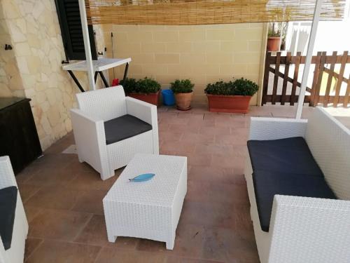 レウカにあるCasa Vacanze salentoの白い椅子とテーブル、植物のあるパティオ