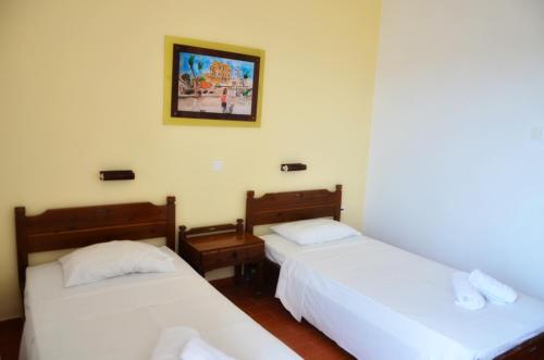 two beds in a room with white sheets at Vagia Beach Apartments, Aegina Island in Vaia