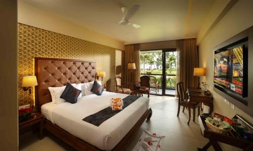 a hotel room with a large bed and a television at Uday Backwater Resort in Alleppey