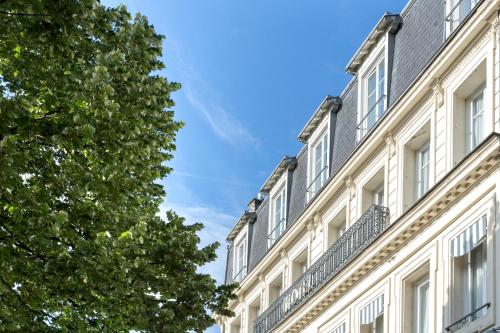a building with white windows and a tree at Best Western Hotel Centre Reims in Reims