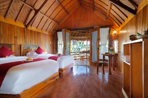 a bedroom with two beds and a table in it at The Tamban Jukung in Nusa Penida