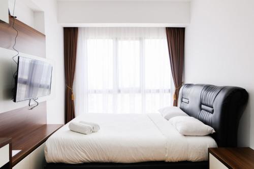a hotel room with a bed and a television at 1BR Apartment at M-Town Residence near Summarecon Mall Serpong By Travelio in Tangerang