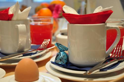 a table topped with cups and plates with utensils and an egg at QuodLibet in Rome