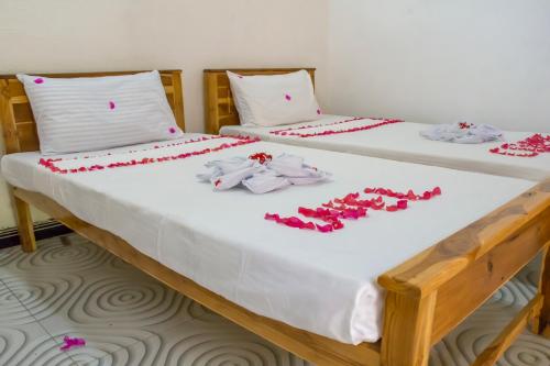 阿魯岡灣的住宿－Beach Lagoon Parans，两张带白色床单和红色鲜花的床