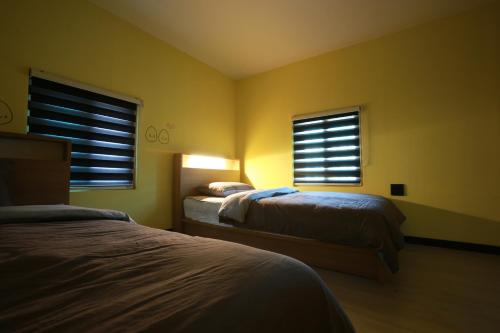 a bedroom with two beds and two windows at Daegwanryeong Egg Guesthouse in Pyeongchang 
