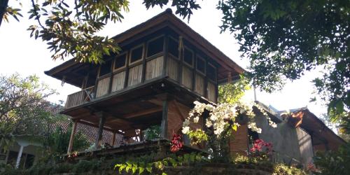 a tree house with a balcony on top of it at ESA di Kubu Homestay in Singaraja