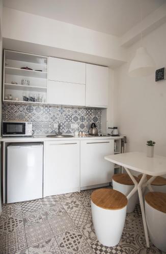 a kitchen with white cabinets and a table with stools at Meidan Suites in Tbilisi City