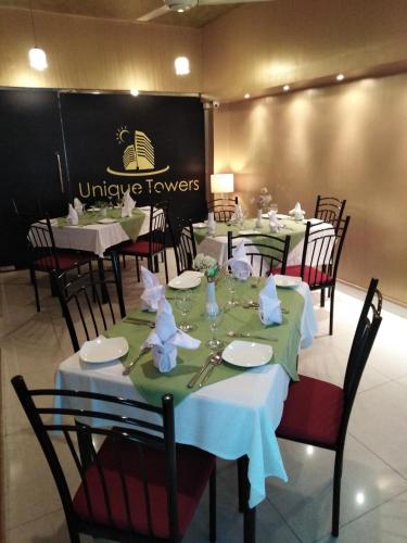 a dining room with tables with white plates and napkins at Unique Towers Luxury Boutique Suites in Colombo