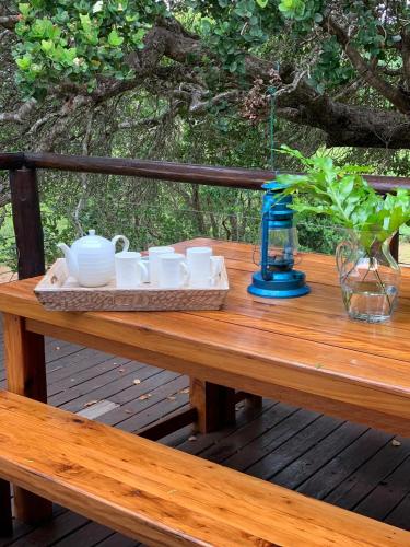 a wooden table with a tray of dishes on it at Nkumbe Bush Retreat Family Home in Ponta Malongane