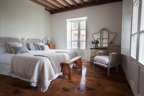 a white bedroom with a large bed and a chair at Posada Seis Leguas in Ríocorvo