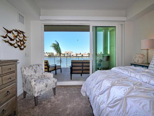 a bedroom with a bed and a chair and a balcony at Sandpiper's Cove 201 Sandpiper's Cove Luxury 3 Bedroom 2 Bathroom 23132 in Clearwater Beach