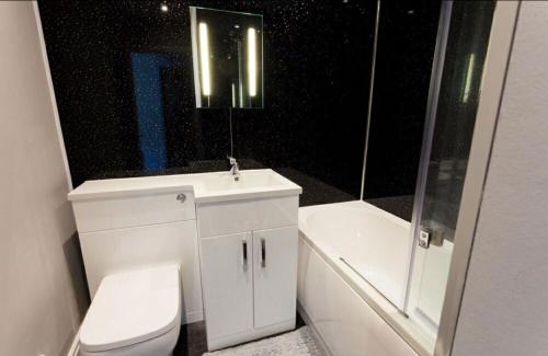 a bathroom with a toilet and a sink and a bath tub at Valley Lodge in Trearddur