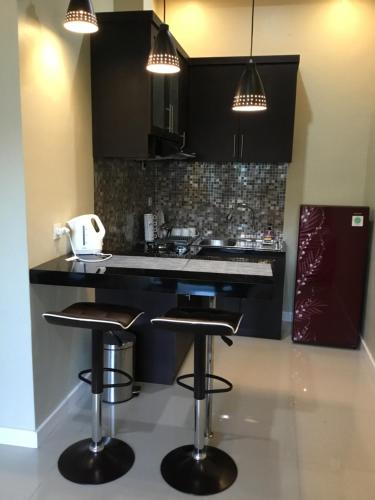 a kitchen with a black counter and stools at The Villa's Kubu Sandan in Kintamani