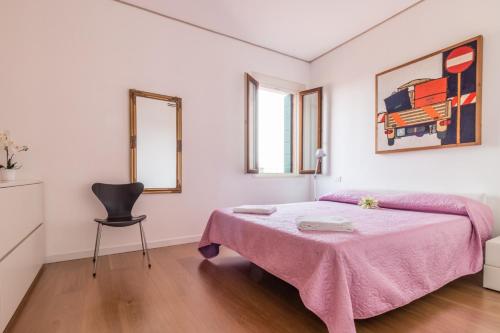 ein weißes Schlafzimmer mit einem rosa Bett und einem Stuhl in der Unterkunft Carmini Canal View and balcony with Lift in Venedig