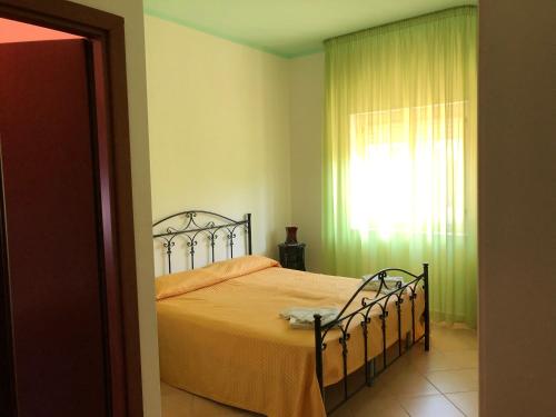 a bedroom with a bed with an orange bedspread and a window at Bed & Breakfast "Camera a Sud" in Cariati