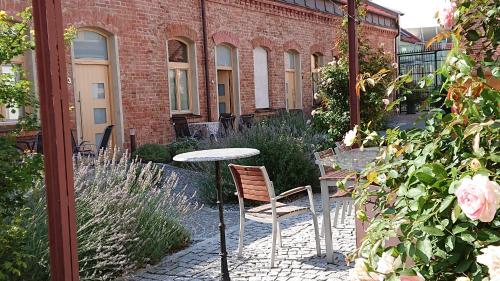 a table and chair in a garden with a brick building at Maison am Liesingbach in Vienna