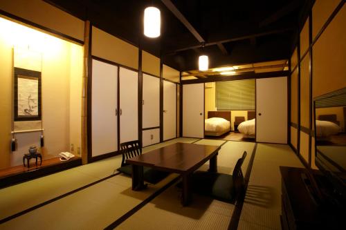a room with a table and a bedroom with two beds at Koyado Enn in Toyooka