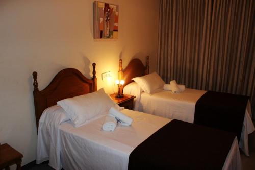a hotel room with two beds and a lamp at Hostal Los Maños in Albentosa