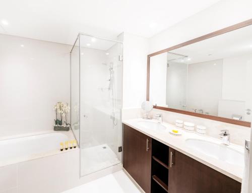 a bathroom with a tub and a sink and a shower at Fantastay - Towering Burj Khalifa view - BLVD Crescent Tower in Dubai