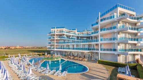 een groot hotel met een zwembad en ligstoelen bij Aparthotel Costa Calma in Aheloy