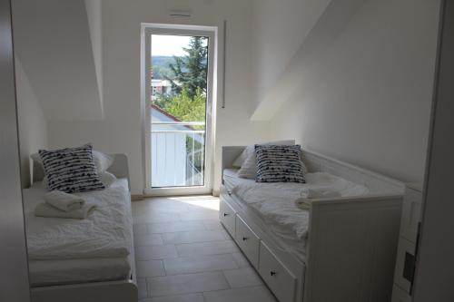 um quarto branco com 2 camas e uma janela em Ferienwohnung Seelicht em Uhldingen-Mühlhofen