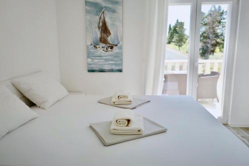 a white bedroom with a bed with towels on it at Apartments Ana Sutivan in Sutivan