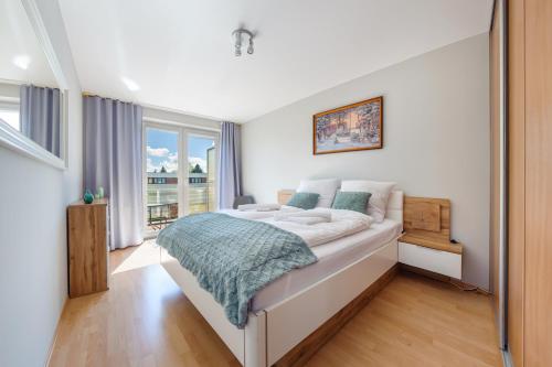 1 dormitorio con cama y ventana grande en Apartamenty Sun & Snow Zielone Tarasy, en Kołobrzeg