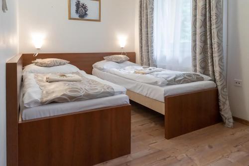 two twin beds in a room with a window at Hotel Granit Smrekovica in Liptovská Osada