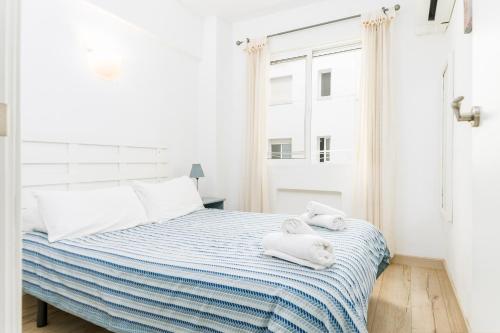 a white bedroom with a bed with towels on it at Suite Homes Malagueta Beach in Málaga