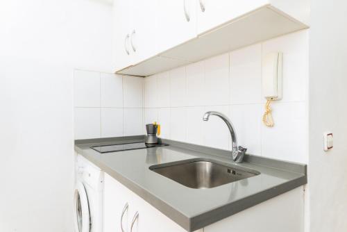 a kitchen with a stainless steel sink and white cabinets at Suite Homes Malagueta Beach in Málaga