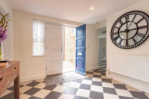 a large clock on the wall in a hallway with a door at The Old Chequers - Hot tub & Games room in Fakenham