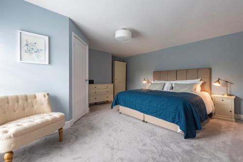 a bedroom with blue walls and a bed and a couch at The Old Chequers - Hot tub & Games room in Fakenham