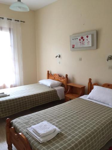 una camera d'albergo con due letti e una finestra di Nikos Apartments a Sidari