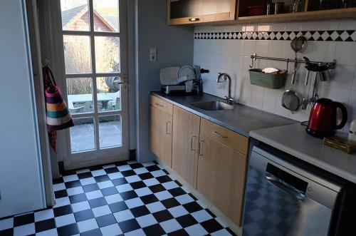 uma cozinha com um lavatório e um piso em xadrez em B&B Madame em Lobith